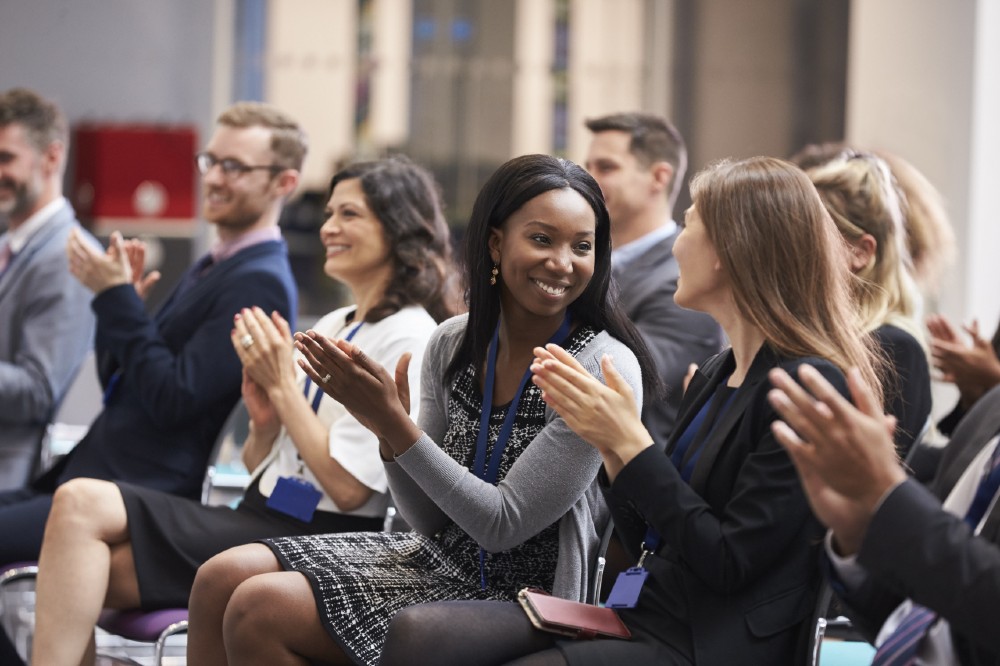 a group of seated men and women applauding